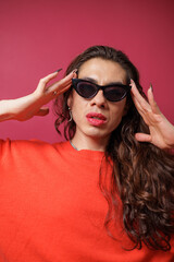 Naklejka premium non-binary person is posing on a red studio background Man has an artistic expression. Concept of non-binary people. pride