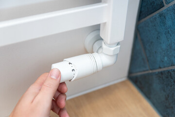 Modern white radiator, hand holding thermostat