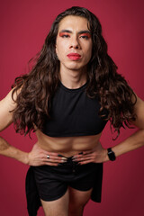 non-binary person is posing on a red studio background Man has an artistic expression. Concept of non-binary people. pride