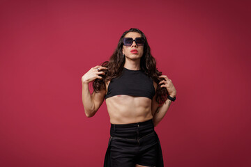 non-binary person is posing on a red studio background Man has an artistic expression. Concept of non-binary people. pride