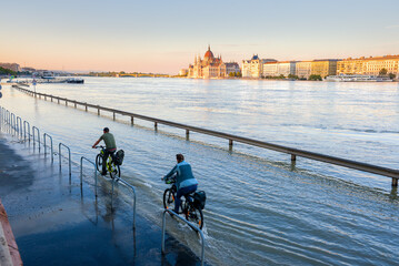 Flooded riverside road in Budapest with bicyclists riding