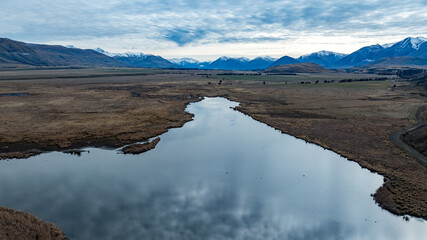 Drone  view of the Ashburton highlands with a river and lake in the dry arid terrain on the way to Lake Heron