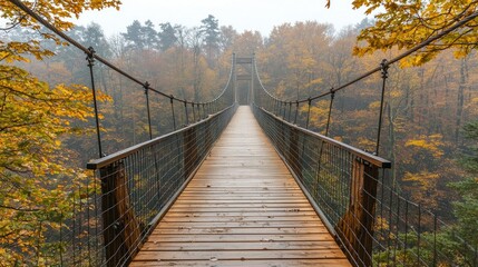 Fototapeta premium Autumn Long bridge spans over a misty gorge, connecting woods on a foggy day