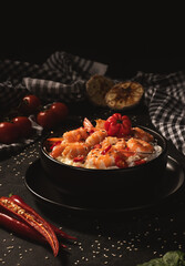 meat with vegetables shrimp in a black bowl with cherry tomatoes