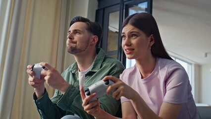 Fototapeta premium Young couple playing online at home sofa closeup. Video players modern hobby