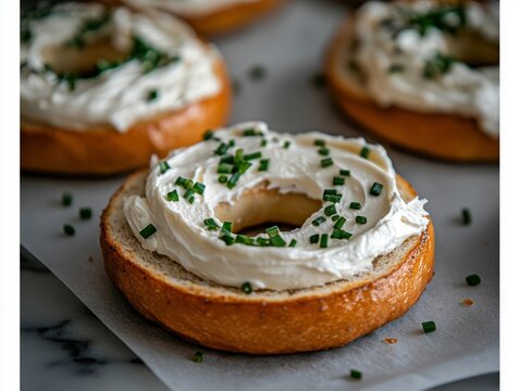 cream cheese slathered on freshly baked bagels with chives sprinkled on top