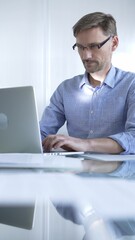 Casual dressed businessman is using a laptop in a contemporary office, with a clean, bright environment that boosts efficiency. Business people concept