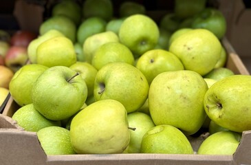 Box filled with fresh natural bio organic green apples placed on counter in local food market. Close-up