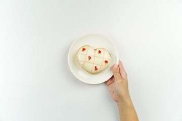 Hand holding Heart Shaped Donut with Pink Icing on Plate