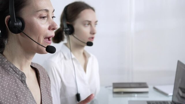 Focused female call center operator in brawn dotted blouse is assisting clients online, providing customer support and answering inquiries. Call center operators