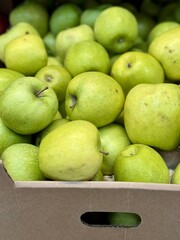 Box filled with fresh natural bio organic green apples placed on counter in local food market. Close-up