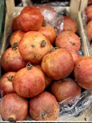 Lots of ripe red pomegranates on a market counter for sale on sale in vegetable stand display at supermarket show organic food