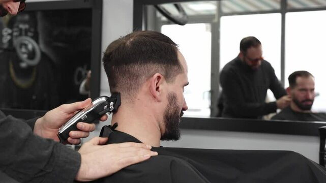 Skilled barber trimming client's hair using electric razor, creating contemporary hairstyle in modern barbershop setting with precise, professional technique