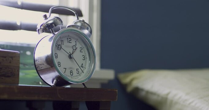 Classic ticking alarm clock on bedroom dresser, medium shot