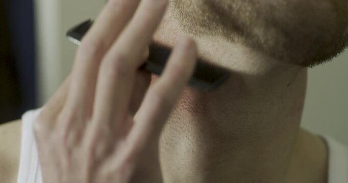 Closeup of man itching irritated neck with comb and flinching