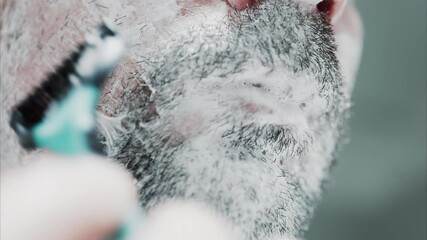 Close up of a man shaving his beard with a razor
