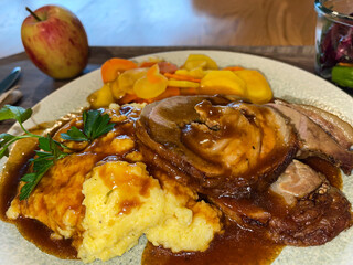 veal roll roast with Polenta, corn porridge with gravy and carrots, traditional Swiss menu in plate, vertical shot