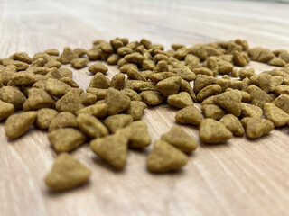 Pet food scattered on wooden surface, highlighting the nutritional shape and texture for canine or feline pets during meal preparation