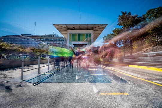 View of the public transport boarding station with passengers deboarding. Spectrum of people in motion caused by the long exposure of photography.