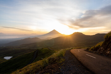 A breathtaking sunrise over a winding mountain road, surrounded by misty valleys and a golden sky. Perfect for travel, adventure, and nature themes. High-resolution stock photo.