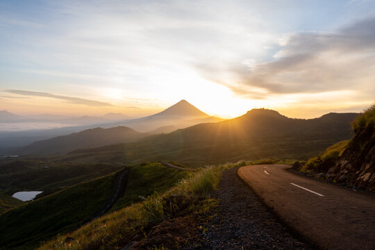 A breathtaking sunrise over a winding mountain road, surrounded by misty valleys and a golden sky. Perfect for travel, adventure, and nature themes. High-resolution stock photo.