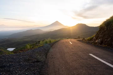Fototapete Cappuccino A breathtaking sunrise over a winding mountain road, surrounded by misty valleys and a golden sky. Perfect for travel, adventure, and nature themes. High-resolution stock photo.  © Ryan