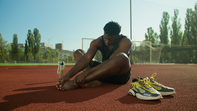 African American man feel ache painful leg pain injured foot after workout outdoors male sportsman footballer guy suffer injury bone finger callus health problem trauma accident on city sport ground