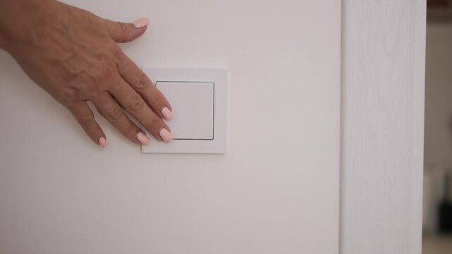 Female hand turns off light using wall switch Closeup of hand pressing switch to stop light in room Concept of saving energy turning off light reducing electricity use and conserving power efficiently