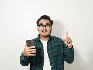 Adult man showing happy expression with finger pointing up when holding mobile phone isolated on white background
