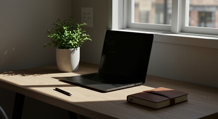 Fototapeta premium Laptop, Notebook, and Plant on Desk Near Window in Sunlight
