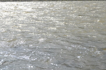 This stunning landscape photo shows a calm river flowing through a lush green valley. The rocks scattered along the riverbank add a natural touch to the view