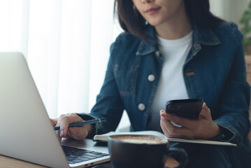 Asian business woman working with laptop computer and using mobile phone, online working at coffee...