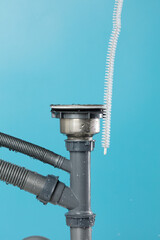 Drain sink leak water from pipe plumbing in kitchen bathroom as water splash clogged drop. Pouring Leaking water from gray plastic pipe drain sink by probe cable. Blue background isolated