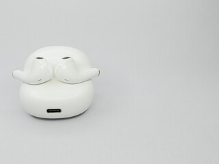 A pair of white wireless earphones with an open case, featuring a modern, elegant and minimalist design, on a white background.