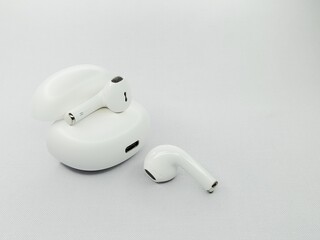 A pair of white wireless earphones with an open case, featuring a modern, elegant and minimalist design, on a white background.