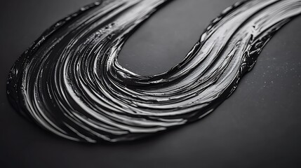 Glossy black paint swirls elegantly across a dark surface, creating a sleek artistic backdrop