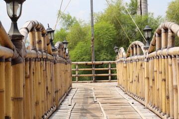 A bamboo bridge in the garden with a background of bamboo leaves and white clouds.
