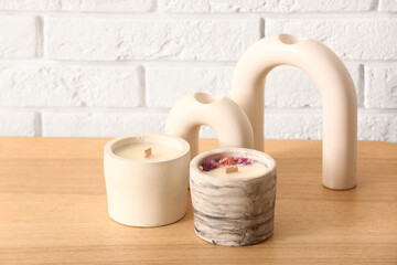Holders with candles and decor on table near light brick wall in room, closeup