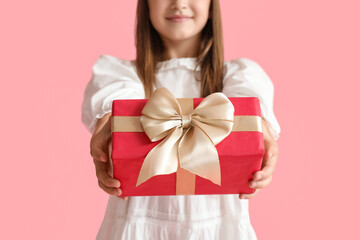 Little girl with gift on pink background, closeup