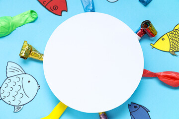 Blank card with paper fishes, balloons and party whistles on blue background. April Fools Day...