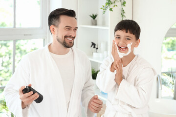 Happy father and his little son applying shaving foam on faces in bathroom