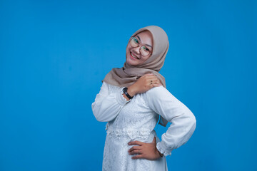 Portrait of Smiling Woman in Hijab holding her shoulders on Blue Background