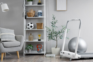Interior of light room with armchair, shelf unit and sports equipment