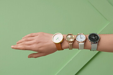 Female hand with wristwatches on green background
