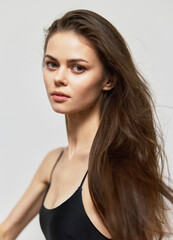 Fototapeta premium Young woman with long hair posing elegantly against a neutral background, showcasing confidence and beauty in a minimalist style. Fashion and portrait concept.