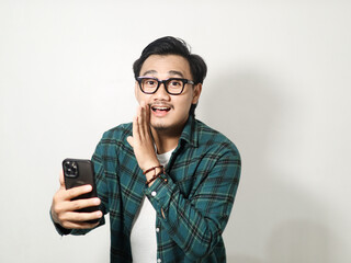 A man whispering something with happy expression while holding mobile phone isolated on white background