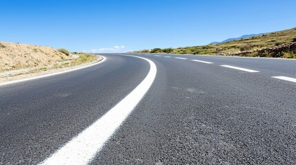 Asphalt road curves gently under a clear blue sky, showcasing a scenic route and open road ahead.