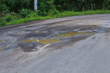 Pothole-ridden road with puddles after rain