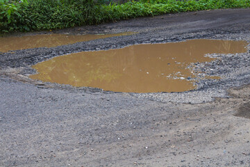 Pothole-ridden road with puddles after rain