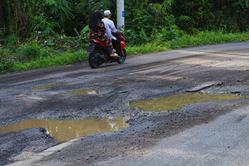 Pothole-ridden road with puddles after rain